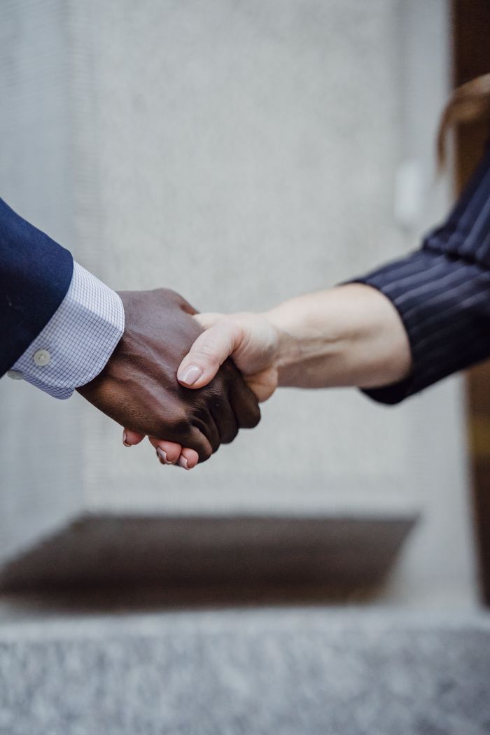 services-04 Close-up photo of diverse hands shaking, symbolizing partnership and cooperation.
